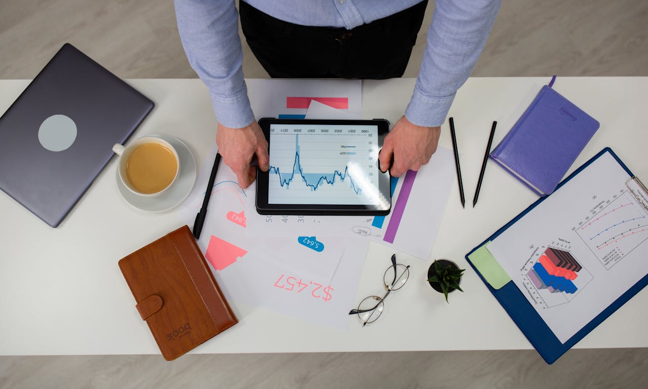 hero-img-01 Overhead view of businessman using tablet to review data charts at a modern office desk.